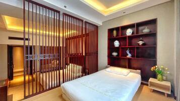 A bedroom with a bed, a wooden partition, a shelf with decorative items, and a nightstand with a vase.