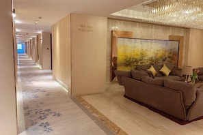 A hotel corridor with a sofa and a painting on the wall.
