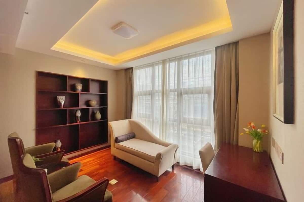A modern living room with a sofa, chairs, a wooden coffee table, and a bookshelf.