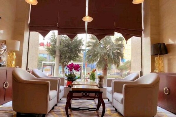 A hotel lobby with two sofas, a table, and a view of palm trees and buildings. - Royal Regent Hotel (Yuhuan)