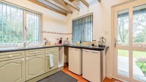 A kitchen with a large window, a sink, and a door leading to a garden.
