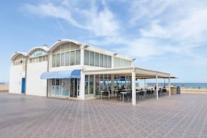 Un restaurant doté d’une terrasse couverte et offrant une vue sur la plage.