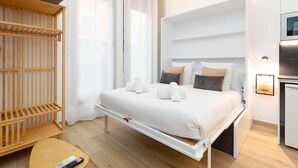 Een moderne hotelkamer met een bed, een houten plank, een tafeltje en een televisie.