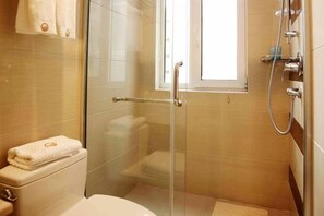 A glass-enclosed shower with a handheld showerhead, a toilet, and a window. - Four Seasons Hotel (Taiyuan l Liuxiang Shanxi Medical University Second Hospital) (Taiyuan)