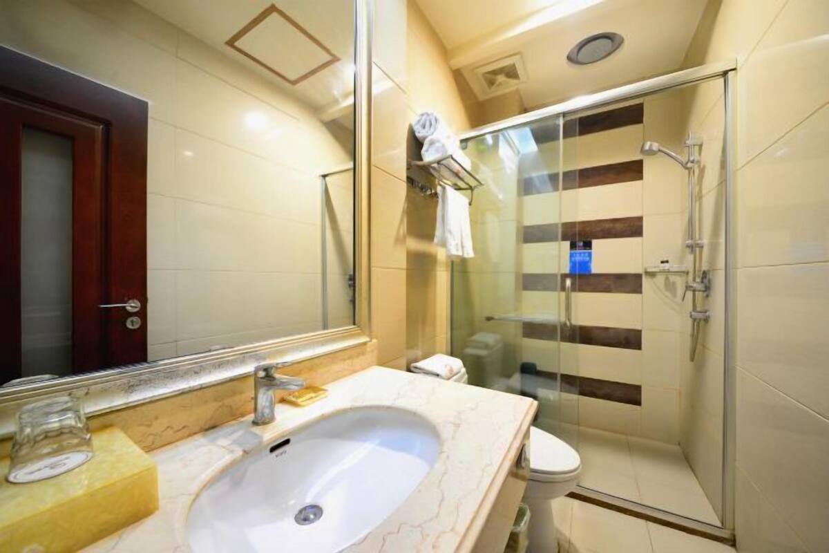A bathroom with a glass-enclosed shower, a sink with a mirror, and a toilet.