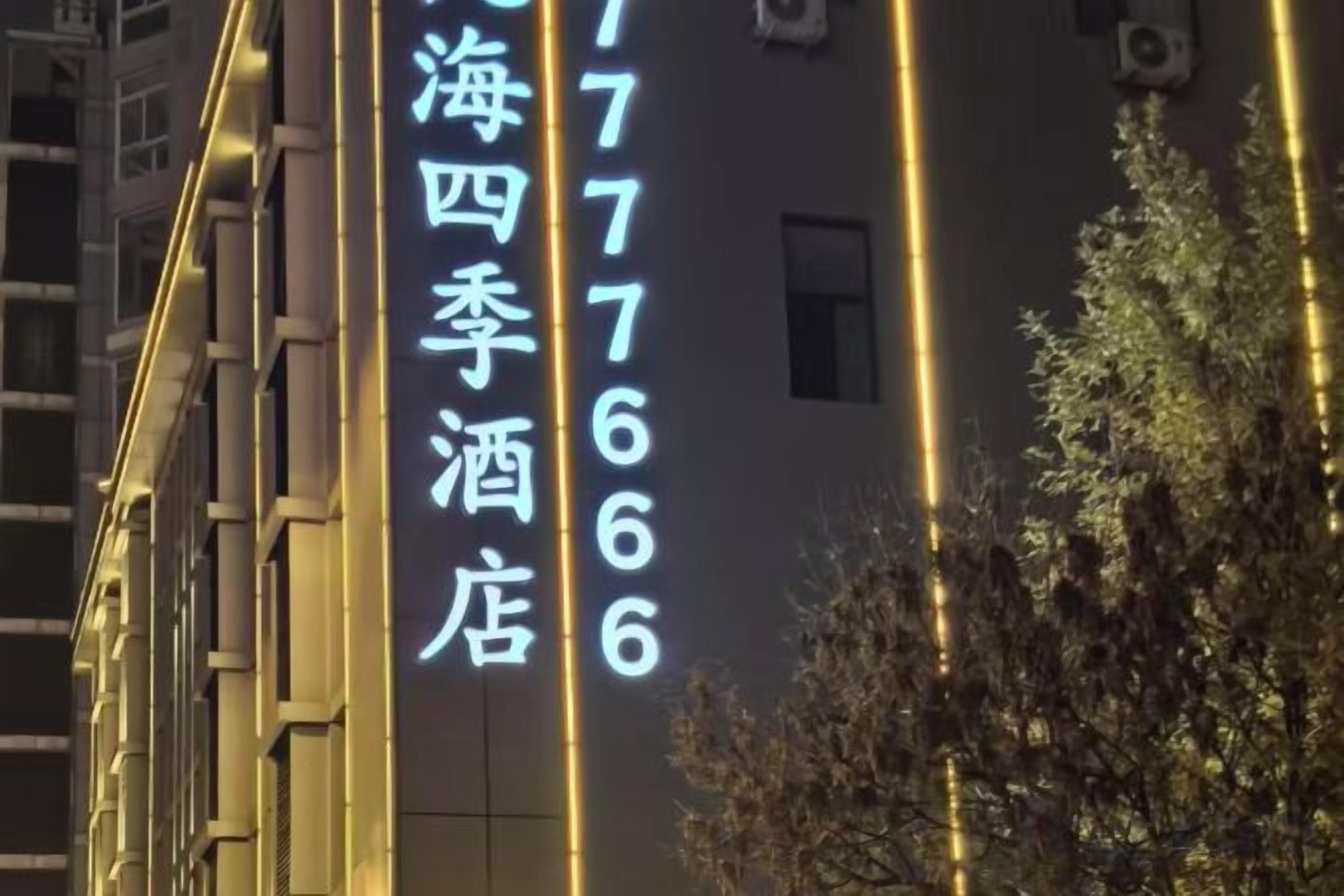 A building with illuminated signage displaying a hotel name and contact numbers.