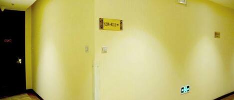 A hotel hallway with a carpeted floor, a sign indicating room number 301, and a light switch on the wall.