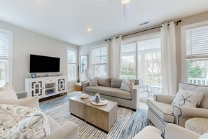 Relax in this stylish living room with a large flat-screen TV, comfortable sofa, and armchair.