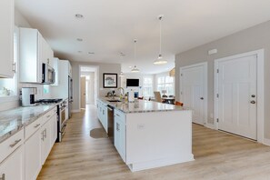 Enjoy cooking in this well-lit kitchen with a central island, white cabinetry, and stainless steel appliances.