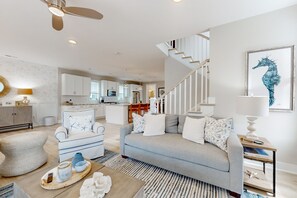 Relax in a stylish living space with a sofa, ottoman, and staircase leading to an upper level.