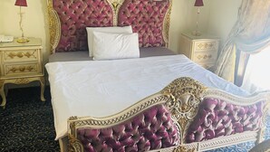 Une chambre à coucher luxueuse, dotée d’un grand lit, d’une tête de lit richement décorée et d’un lustre.