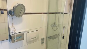 Une salle de bain moderne avec une douche à parois de verre, des toilettes, un lavabo et un miroir rond.