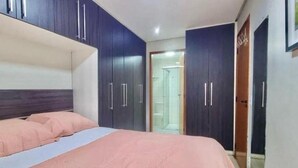 Ein Schlafzimmer mit einem Bett, einem dunkelblauen Kleiderschrank und einer Tür zum Badezimmer.