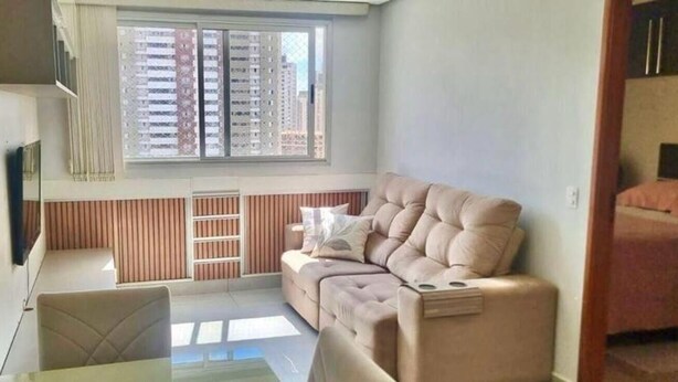 Ein gemütlicher, kleiner Wohnraum mit einer Couch, einem Tisch und einem Fenster mit Jalousien.