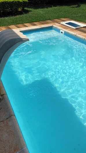 Una piscina al aire libre, sillones reclinables de piscina