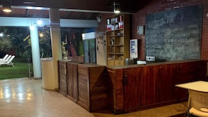 Un espacio al aire libre con barra de madera, un menú en la pizarra y una zona de estar con mesa y sillas.