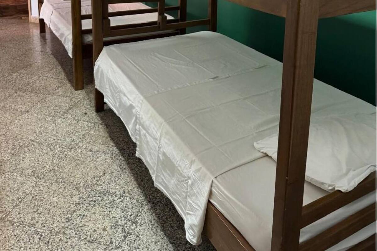 Tweepersoonsbed in een kamer met groene wanden en een houten plafond.