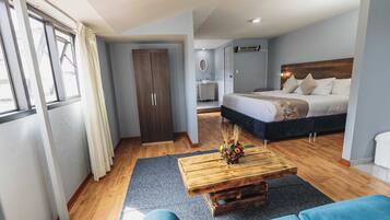 A bedroom with a bed, a wooden coffee table with a flower arrangement, a wardrobe, and a bathroom visible in the background.