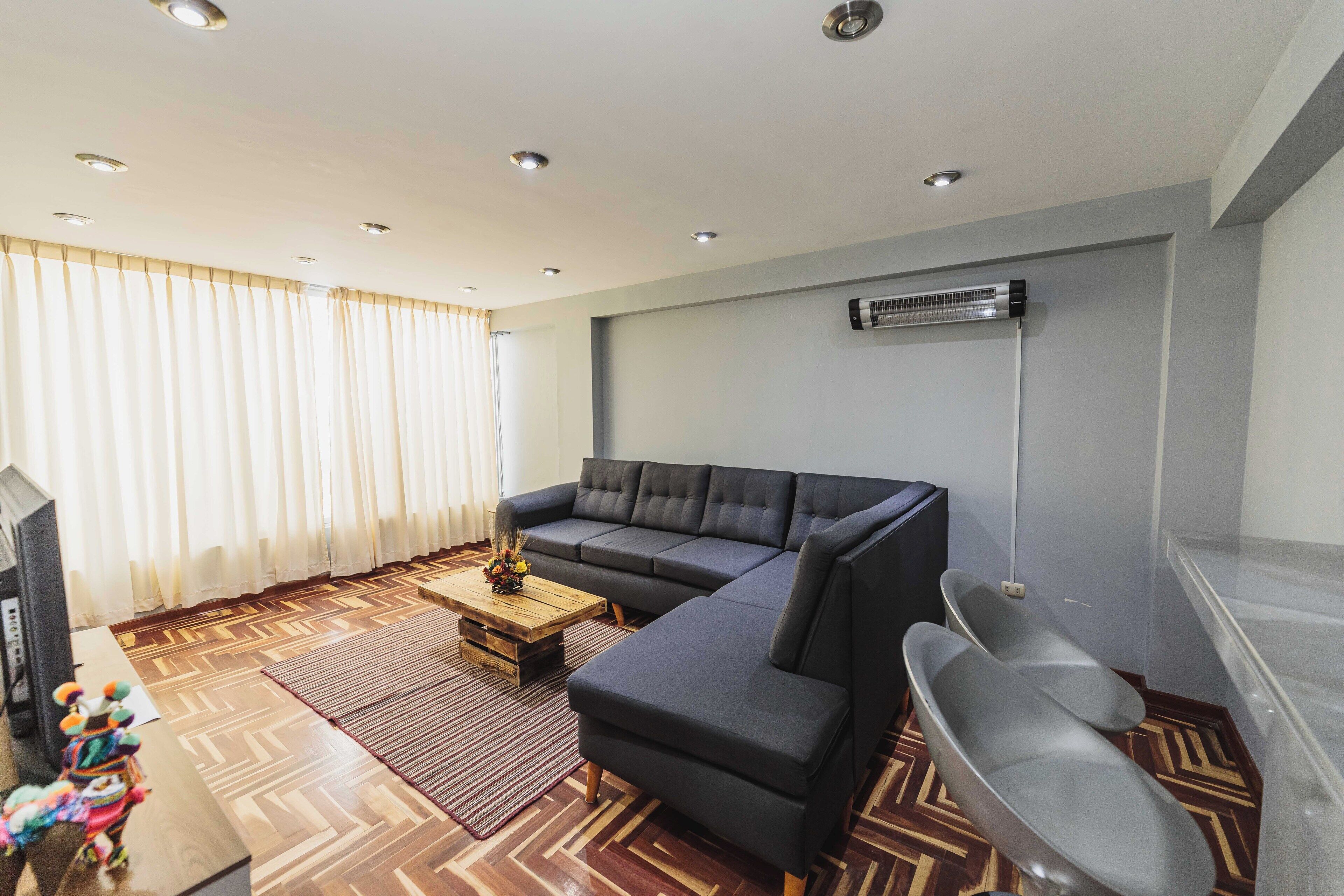 Una sala de estar moderna con un sofá modular, una mesita de centro de madera y un sillón gris.