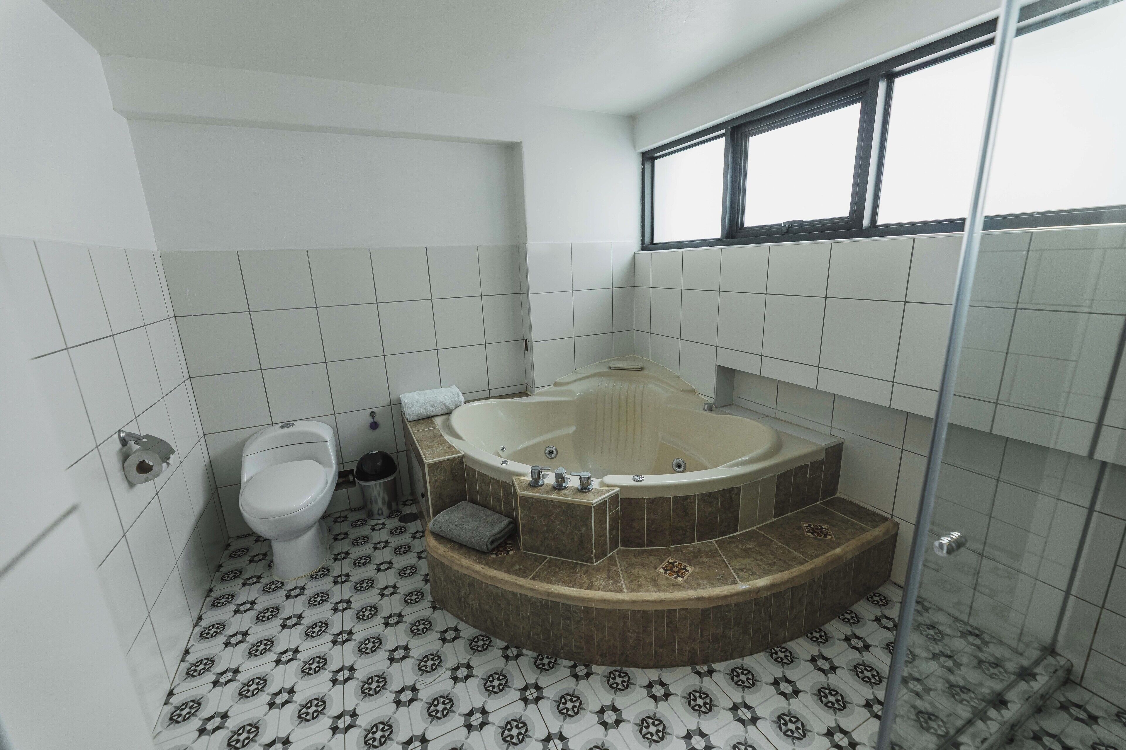 Et badeværelse med toilet, badekar og bruser.
