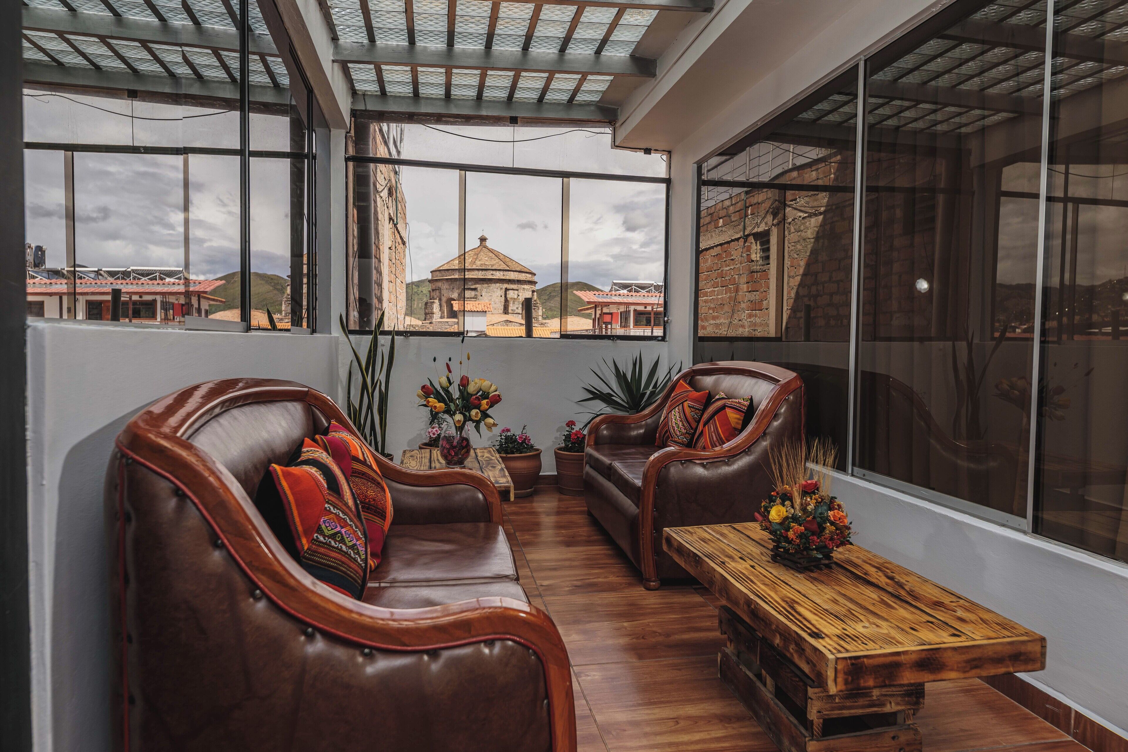 A spacious room with leather sofas, a wooden coffee table, and large windows offering a view of a distant building.