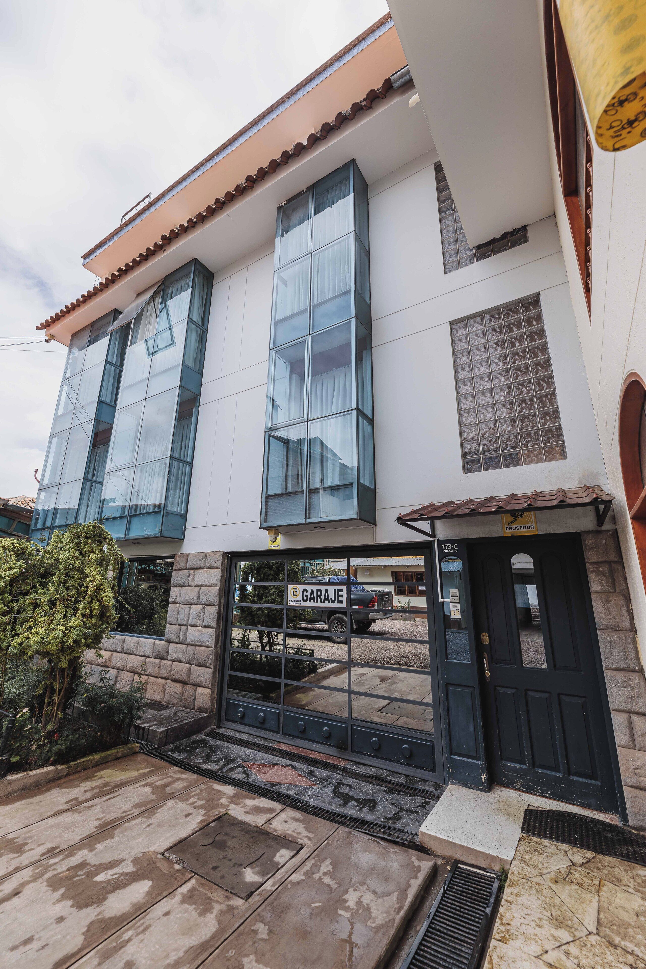 Un edificio de dos pisos con amplios ventanales, entrada de garaje y fachada de piedra.