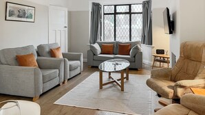 A modern living room with grey sofas, a glass coffee table, and a beige armchair. - 3 bedroom accommodation in Keswick (Keswick)