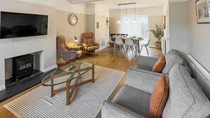 A modern living room with a sofa, chairs, a coffee table, a TV, and a fireplace. - 3 bedroom accommodation in Keswick (Keswick)