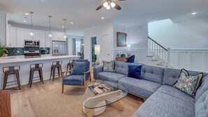 A modern living room with a large sofa, a glass coffee table, and a kitchen area in the background. - Dreamland in the Brooklyn Arts District (Wilmington)