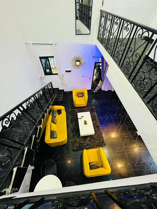 A modern interior with a staircase, black and yellow furniture, and a decorative mirror.