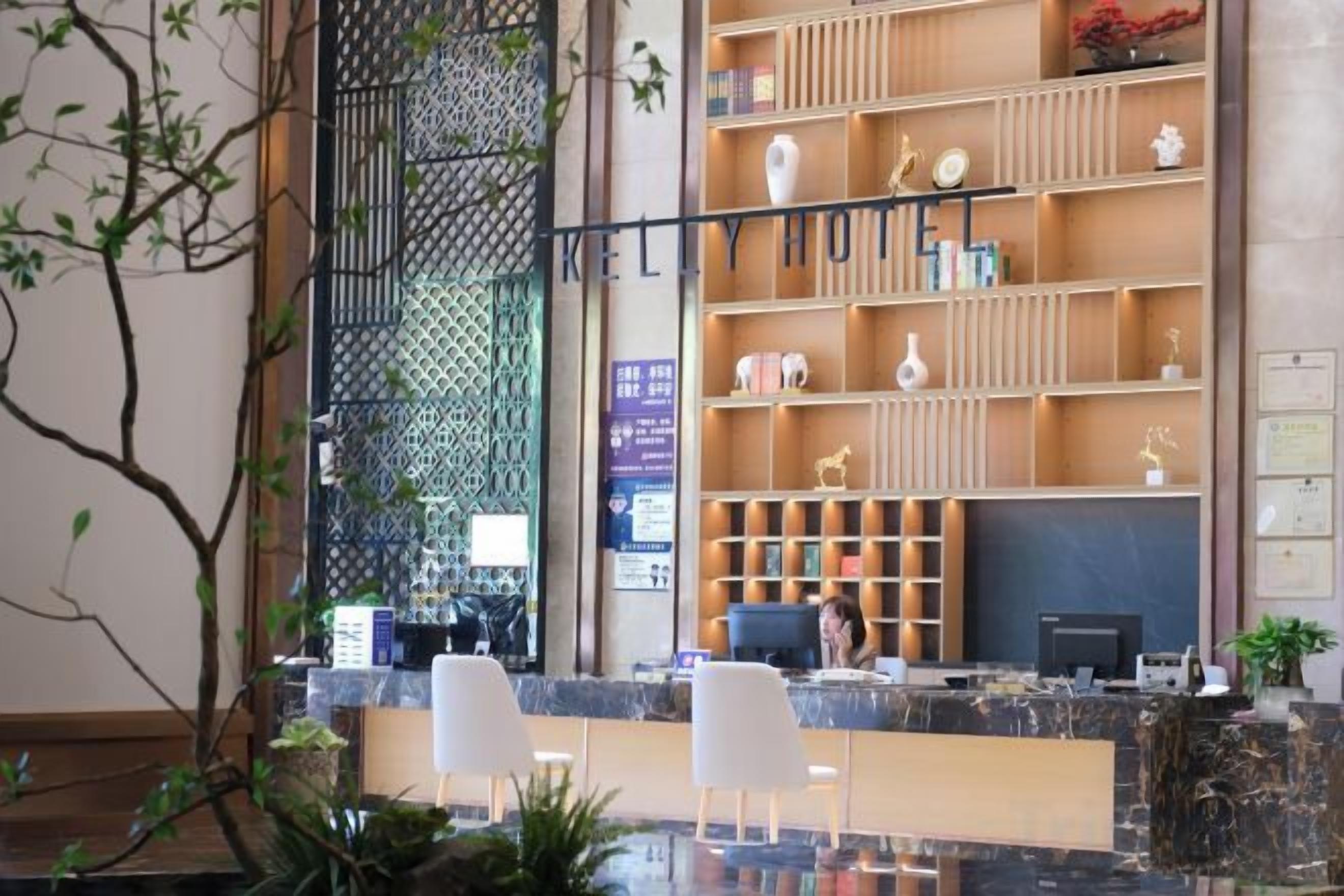 A reception area with a counter, white chairs, and a decorative shelving unit with various items.
