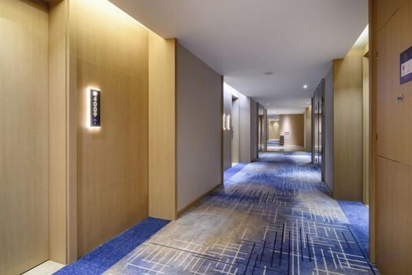 A hotel corridor with a carpeted floor, wooden walls, and a sign indicating the direction to the social area.