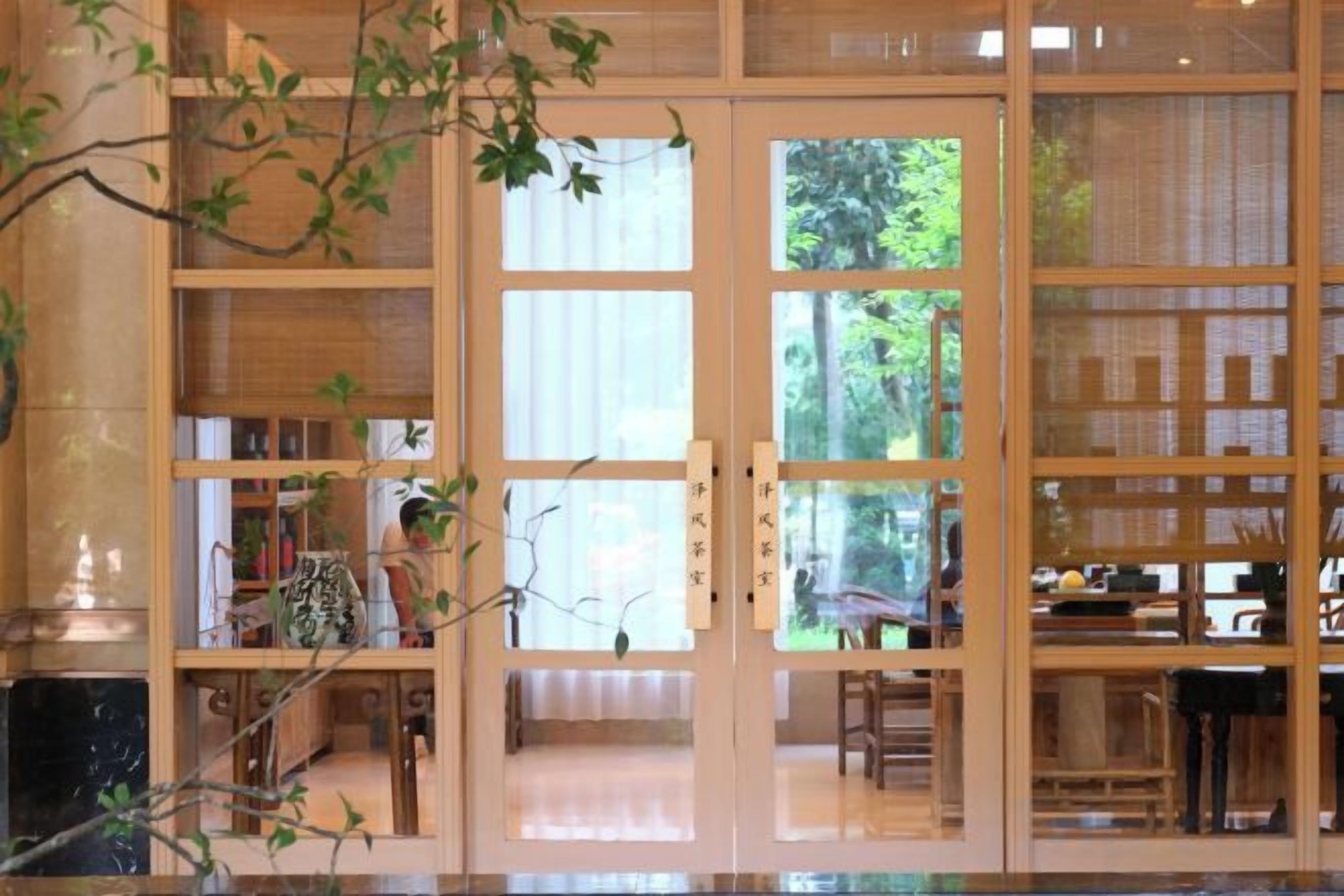 Et traditionelt japansk interiør med skydedøre, et spiseområde og udsigt til grøn natur udenfor.