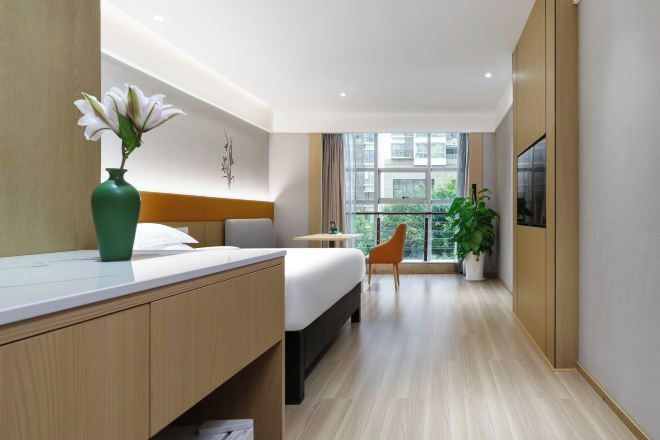 A modern hotel room with a bed, bedside table, and a large window offering a view.