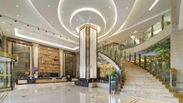 Un hall d’entrée spacieux, doté d’une colonne centrale, d’un escalier et d’un espace de réception avec des étagères.