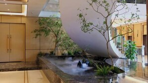 Un intérieur moderne agrémenté d’un élément aquatique, de plantes d’intérieur et d’un mur incurvé.