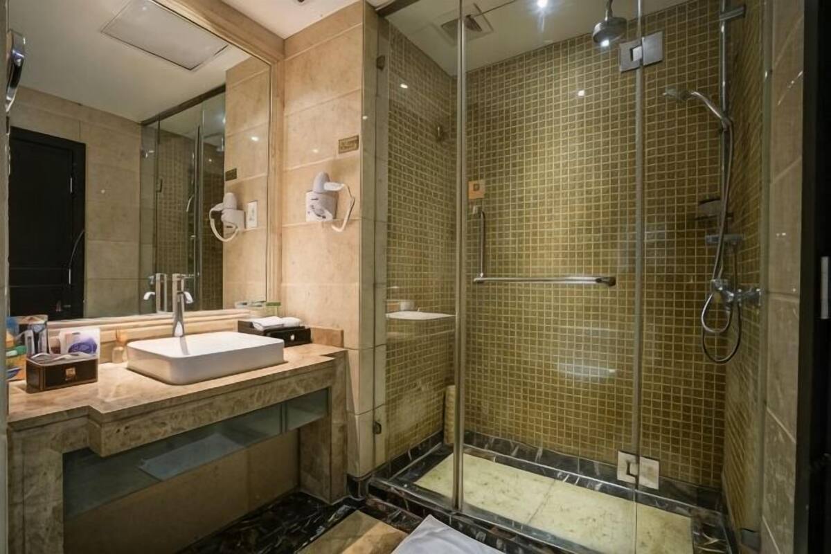 A modern bathroom with a glass-enclosed shower, a sink with a mirror, and a vanity with toiletries.