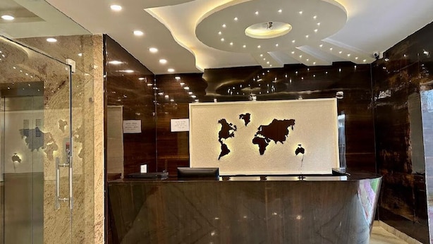 A reception area with a marble counter, a world map, and a modern ceiling design. - The Elgin Hotel (Kolkata)