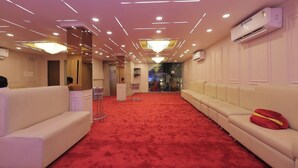 A hotel lobby with a red carpet, white sofas, and a chandelier. - The Elgin Hotel (Kolkata)