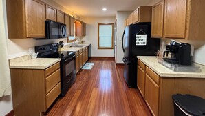 A kitchen with wooden cabinets, a black refrigerator, a black stove, a microwave, and a coffee maker. - Cozy Corner Cottage - 4 Bed/2 Bath
No Cleaning Fee! (Salina)