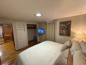 Una camera da letto con un letto, una televisione a muro, un quadro e una lampada.