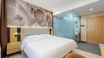 A hotel room with a large bed, a nightstand, a chair, a glass partition, and a wooden door.