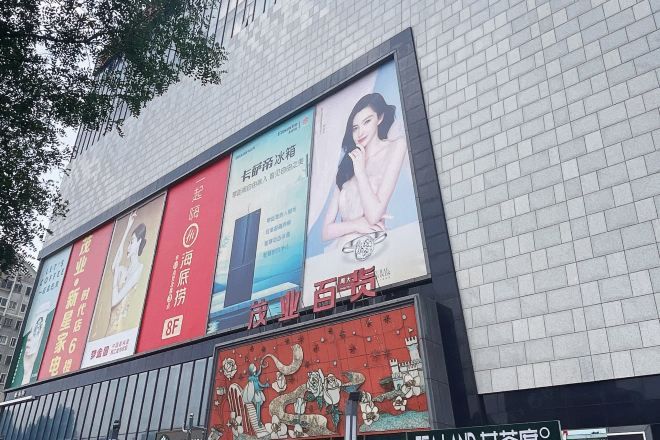 A building facade with multiple advertisements, including a prominent red banner and a blue banner with a woman.