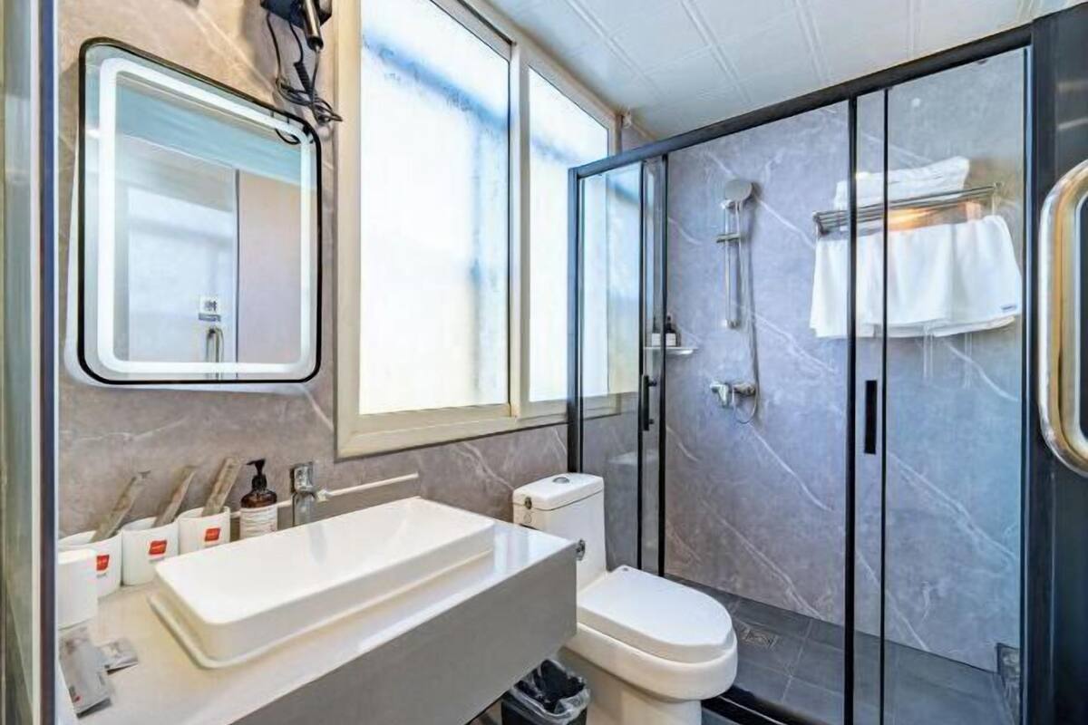 Un baño moderno con cabina de ducha de vidrio, un lavabo blanco y un inodoro.