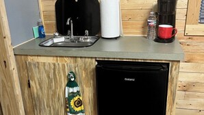 Eine kleine Küche mit Spüle, Kaffeemaschine und Kühlschrank.