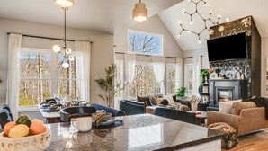 A spacious living area with a large kitchen island, a fireplace, and a dining area. - 4k SqFt, Massive Deck , Games, Spa, Sauna, Firepit (Hendersonville)