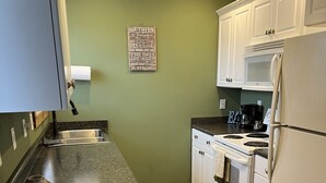 A kitchen with white cabinets, a granite countertop, a stove, and a refrigerator. - Charming 1-bedroom house in Paris, TN. (Paris)