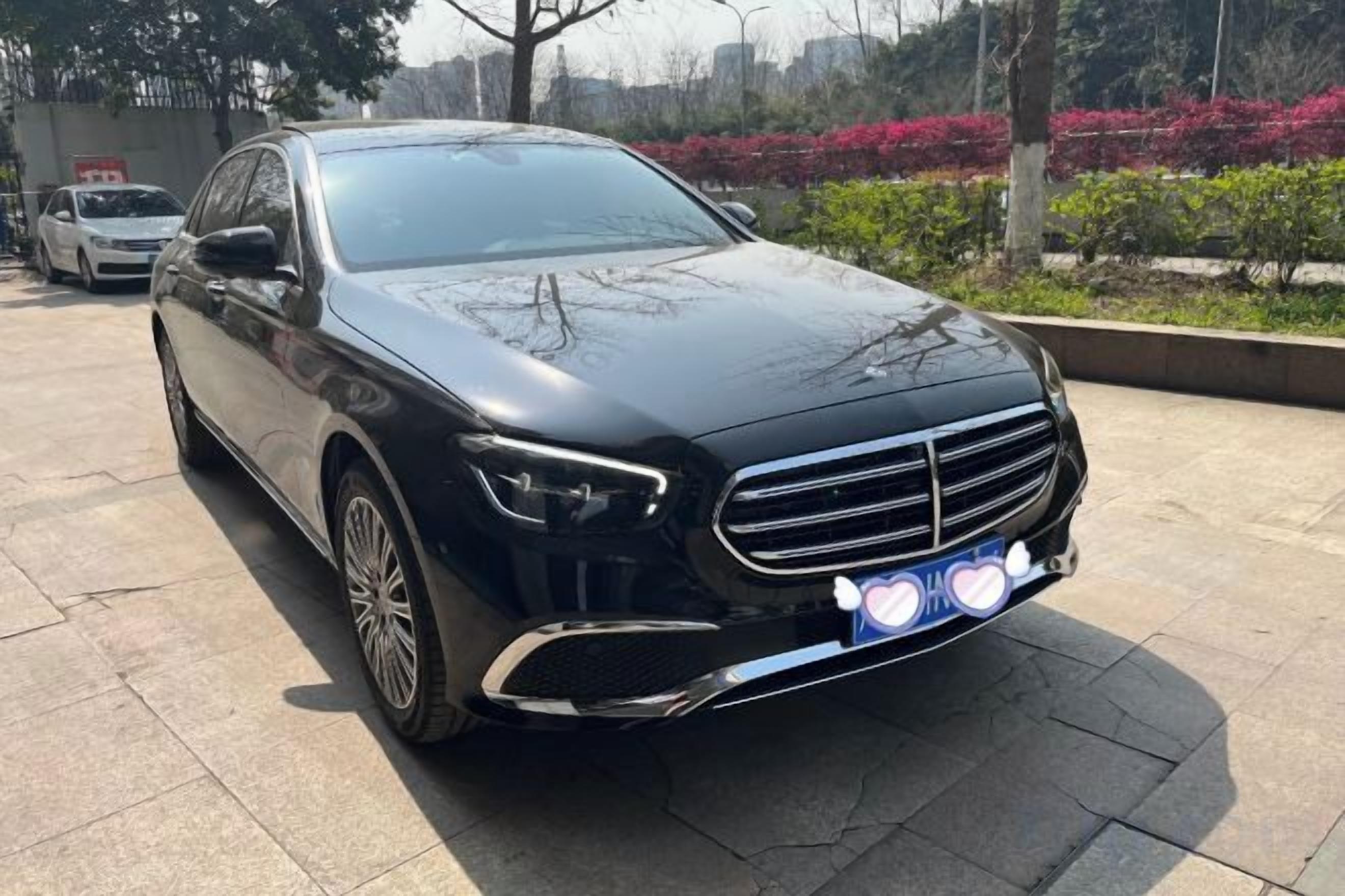 A black car parked on a paved surface with a clear sky in the background.