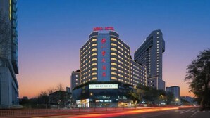 Ein mehrstöckiges Hotel mit einer markanten roten Signatur auf dem Dach, mehreren Balkonen und einem modernen architektonischen Design.