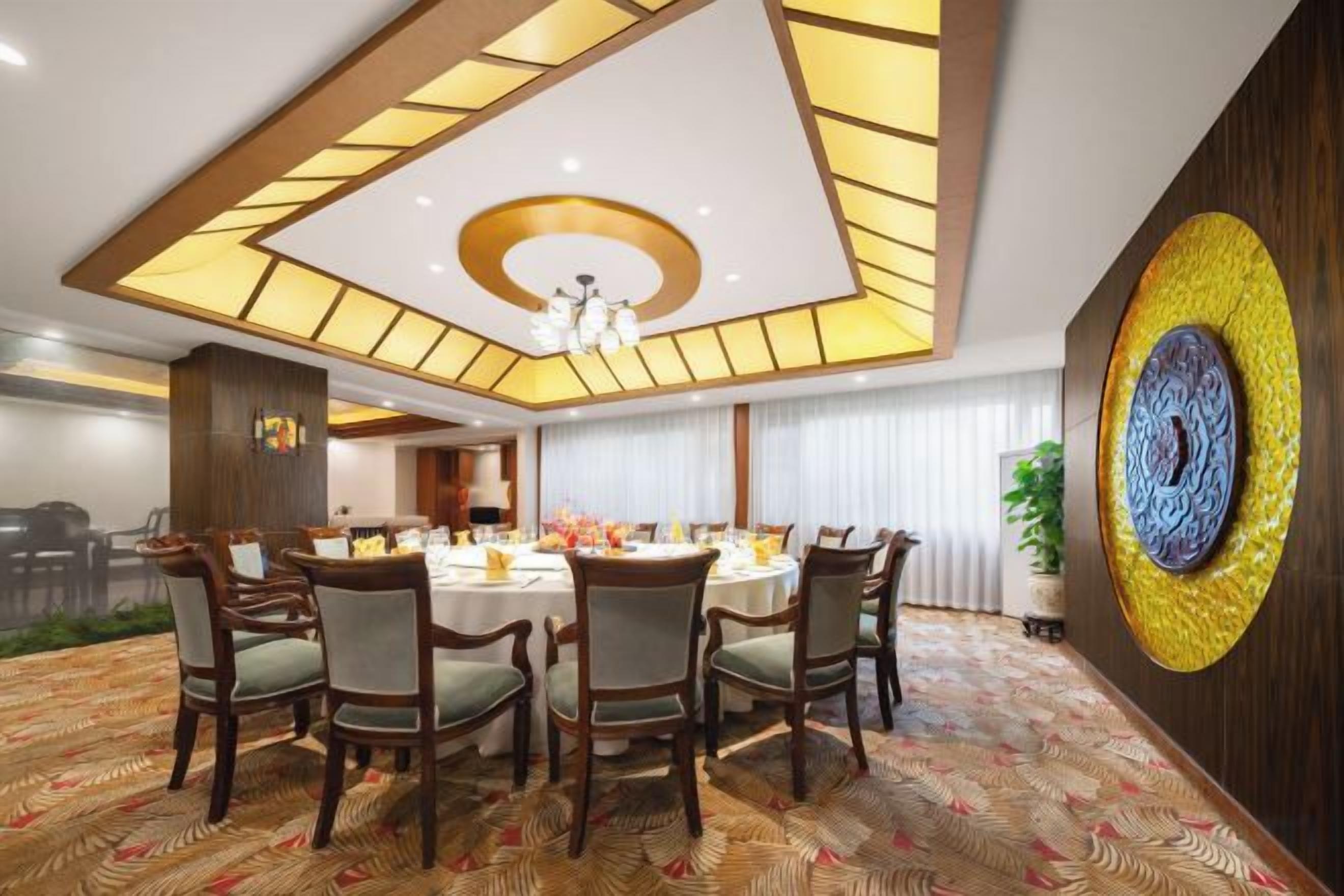 A conference room with a round table, chairs, and a patterned carpet.